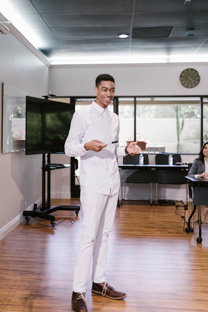 Confident man presenting in a modern office with colleagues seated.